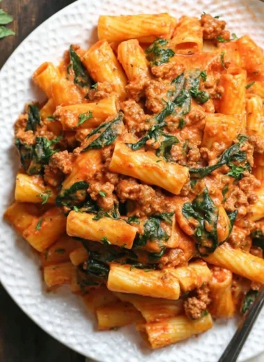 Creamy sausage rigatoni pasta dish with fresh spinach in a white sauce