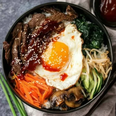 A colorful bowl of Bibimbap topped with vegetables and a fried egg