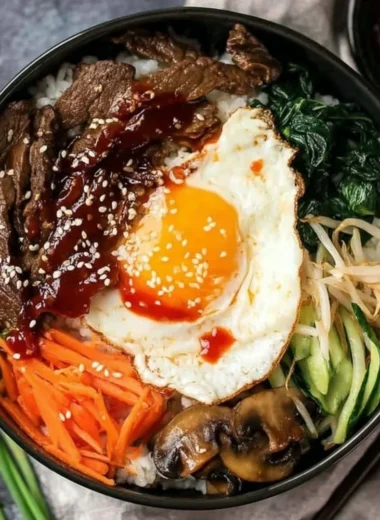 A colorful bowl of Bibimbap topped with vegetables and a fried egg