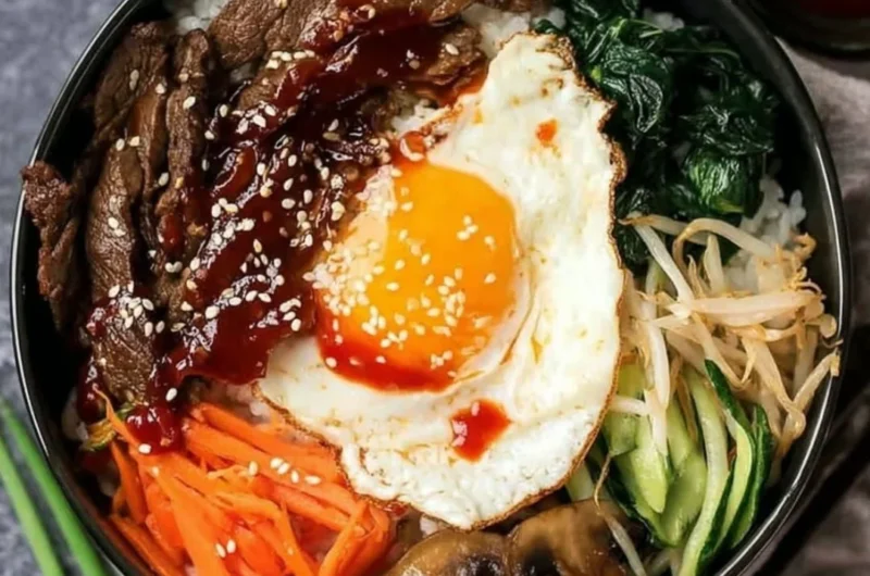 A colorful bowl of Bibimbap topped with vegetables and a fried egg