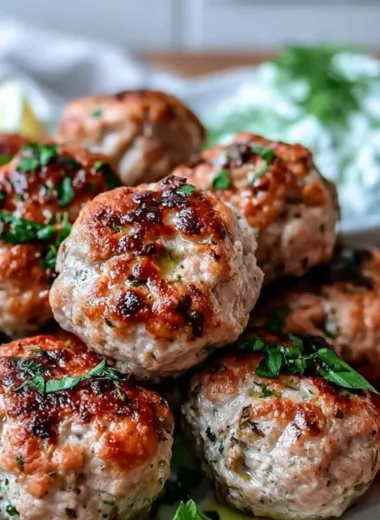 Plate of Greek turkey meatballs with tzatziki sauce garnished with fresh herbs
