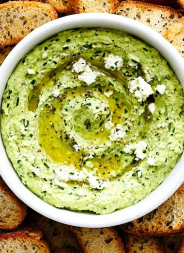 Green Goddess Feta Dip with herbs in a bowl, served with colorful vegetables.