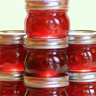 Jar of homemade rhubarb cinnamon jam with fresh rhubarb stalks in the background
