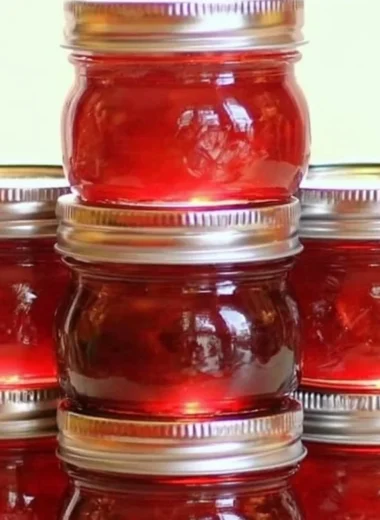 Jar of homemade rhubarb cinnamon jam with fresh rhubarb stalks in the background