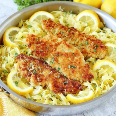 Plate of Romano Chicken served with lemon garlic pasta and garnished with herbs.