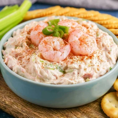 Delicious shrimp dip served in a bowl with fresh herbs and crackers