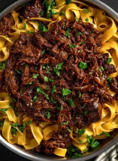 Bowl of slow-cooked short rib ragù with pasta and fresh herbs