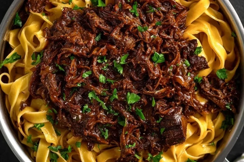 Bowl of slow-cooked short rib ragù with pasta and fresh herbs