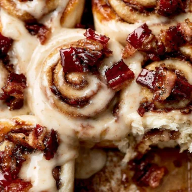 Delicious Bourbon Maple Bacon Cinnamon Rolls topped with frosting and pecans