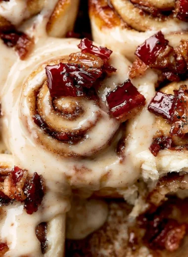Delicious Bourbon Maple Bacon Cinnamon Rolls topped with frosting and pecans