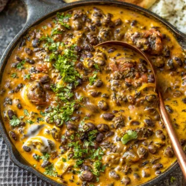Bowl of Easy Creamy Black Bean Curry served with rice and herbs