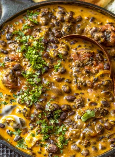 Bowl of Easy Creamy Black Bean Curry served with rice and herbs