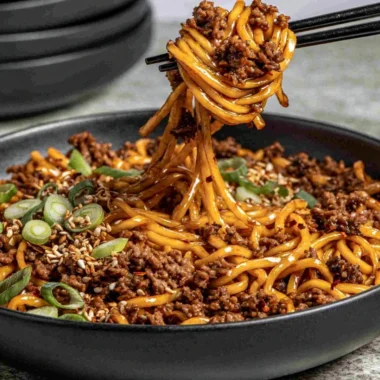 Plate of easy Mongolian ground beef noodles garnished with green onions