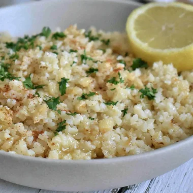 Delicious Garlic Butter Cauliflower Rice in a bowl, garnished with herbs.