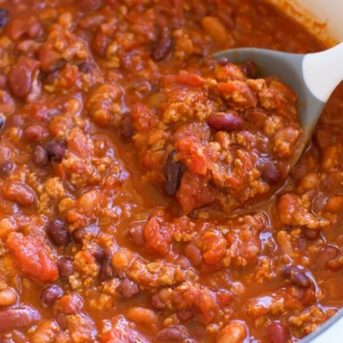 A bowl of healthy turkey chili garnished with fresh herbs and spices.