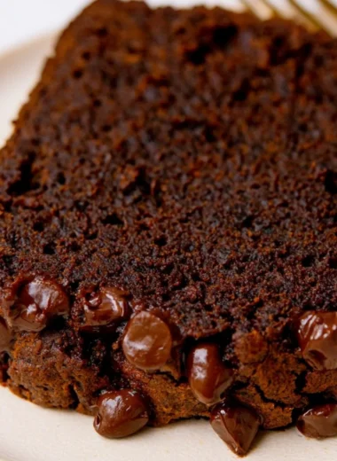Slice of double chocolate pumpkin bread with chocolate chips on a rustic table
