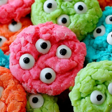 A plate of gooey monster cookies filled with chocolate chips and colorful candies.