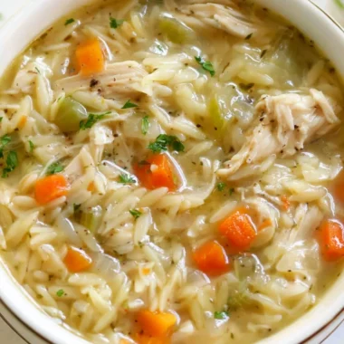 Bowl of Lemon Chicken Orzo Soup with fresh herbs and lemon slices