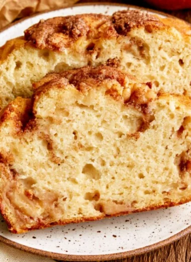 A loaf of moist and tender cinnamon apple bread garnished with cinnamon sticks